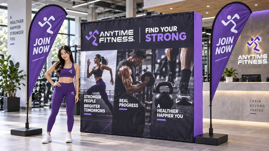 Anytime Fitness concept with a premium custom pop up media wall, purple teardrop banners and a model wearing matching purple gym activewear.